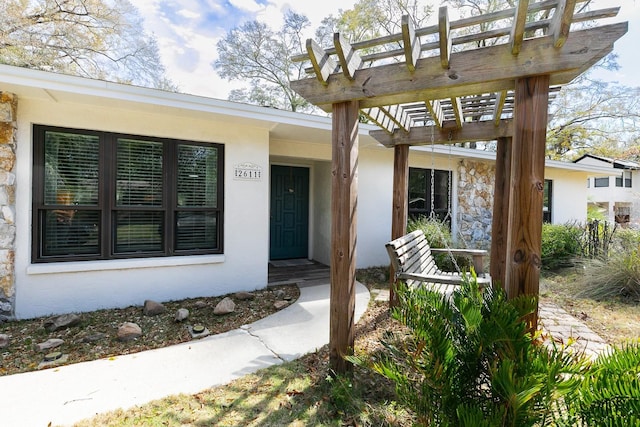 doorway to property with stucco siding and a pergola