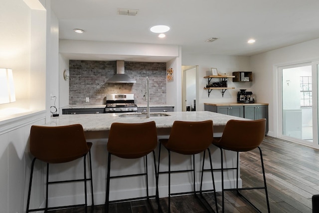 kitchen with visible vents, backsplash, stainless steel range with gas cooktop, wall chimney exhaust hood, and dark wood-style flooring