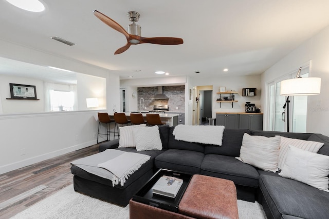 living room with a ceiling fan, wood finished floors, visible vents, baseboards, and recessed lighting