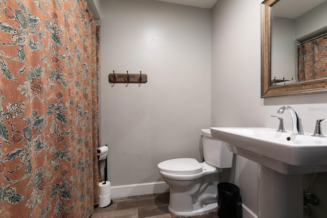 bathroom with a shower with shower curtain, baseboards, toilet, and wood finished floors