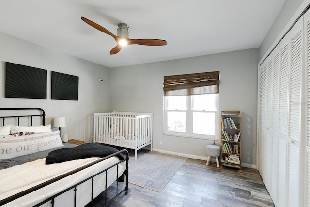 bedroom featuring ceiling fan, a closet, baseboards, and wood finished floors