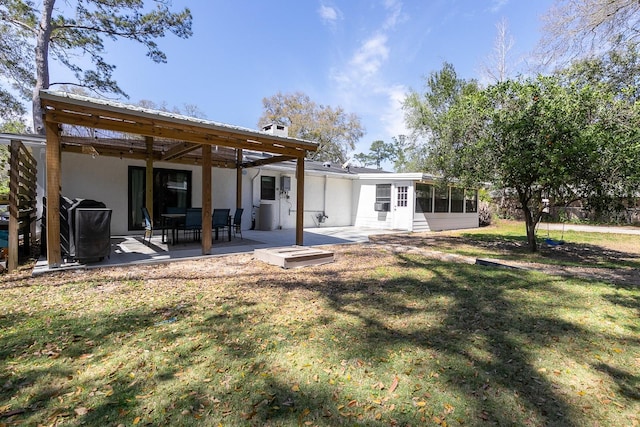 back of house featuring stucco siding, metal roof, a yard, a sunroom, and a patio