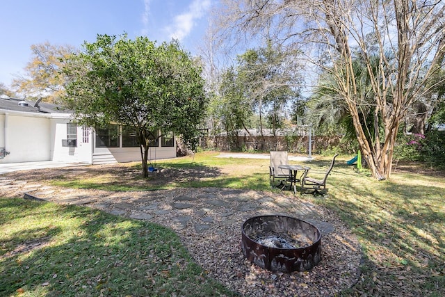 view of yard featuring a sunroom, a fire pit, a patio, and fence