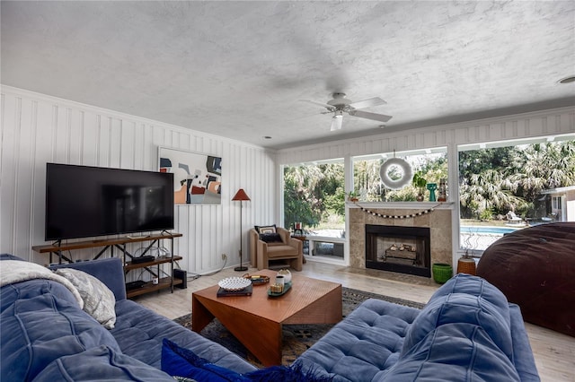 living room featuring a tile fireplace, a textured ceiling, and wood finished floors