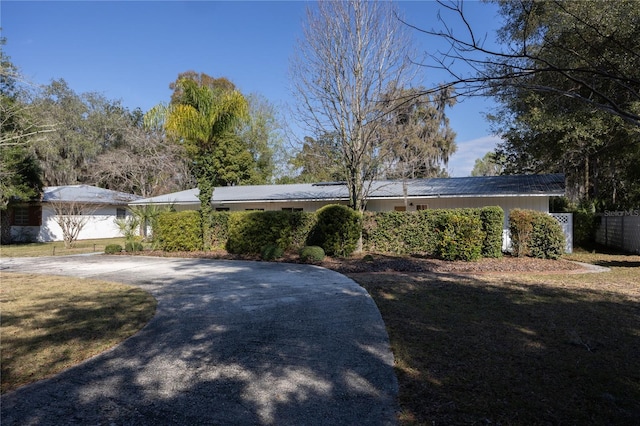 ranch-style house featuring driveway, a front yard, and fence