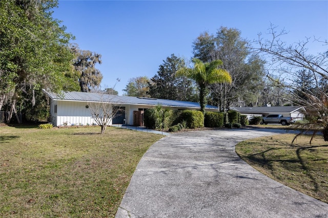 single story home with metal roof, driveway, and a front lawn