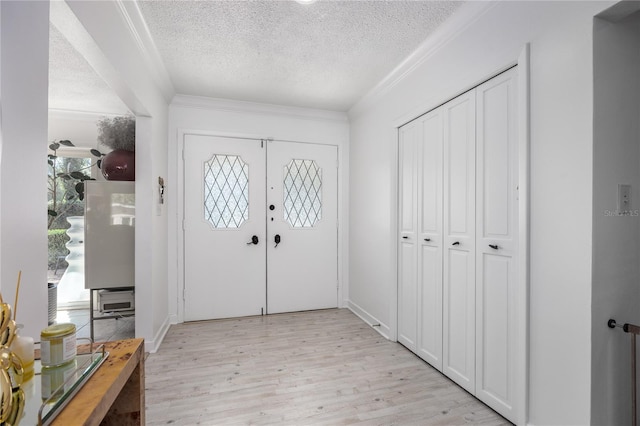 entryway with ornamental molding, light wood-style flooring, and a textured ceiling