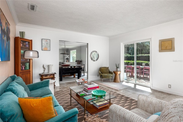 living room featuring ornamental molding, visible vents, a textured ceiling, and baseboards