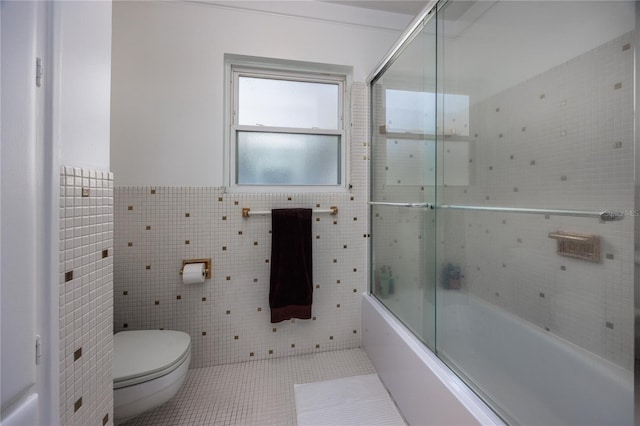 bathroom with toilet, combined bath / shower with glass door, tile walls, and tile patterned floors