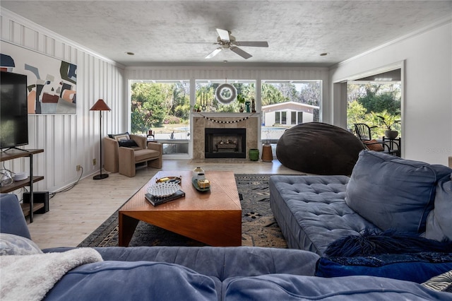 living room featuring a textured ceiling, a healthy amount of sunlight, wood finished floors, and crown molding