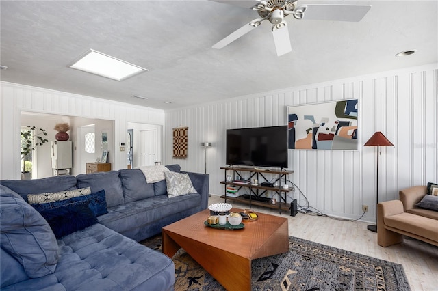 living room featuring ceiling fan, ornamental molding, and wood finished floors