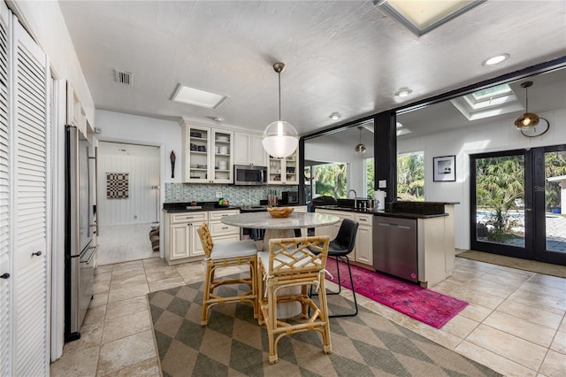 kitchen with visible vents, glass insert cabinets, a breakfast bar area, stainless steel appliances, and french doors