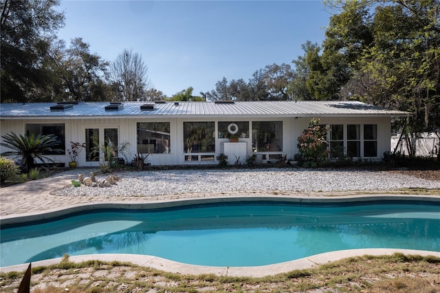 rear view of house featuring an outdoor pool and metal roof