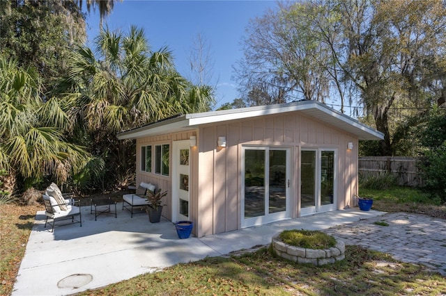 back of house with a patio area, fence, board and batten siding, and an outbuilding