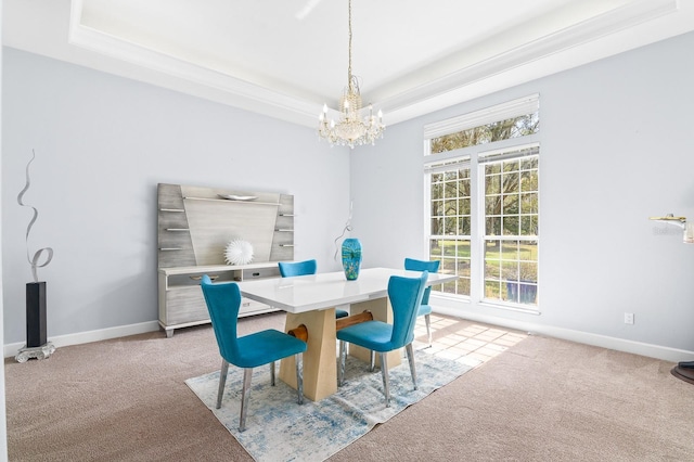 dining space with light carpet, a tray ceiling, baseboards, and an inviting chandelier