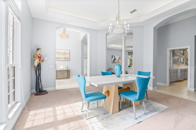 dining area featuring arched walkways, a tray ceiling, light colored carpet, visible vents, and an inviting chandelier