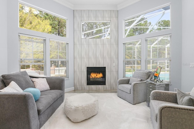 living area with a large fireplace, crown molding, and a high ceiling