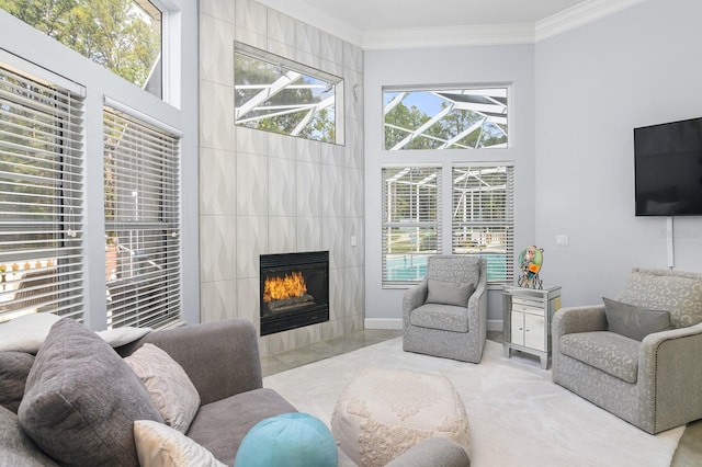 living room featuring ornamental molding, baseboards, a fireplace, and a high ceiling