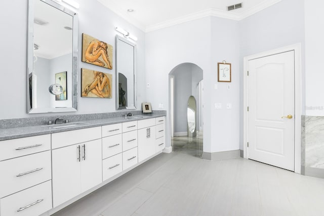 full bathroom featuring double vanity, visible vents, ornamental molding, a sink, and baseboards