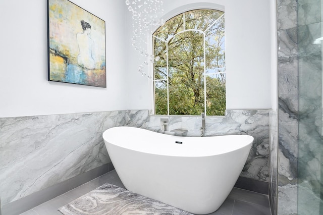 full bath featuring a wainscoted wall, tile patterned flooring, a freestanding tub, and tile walls