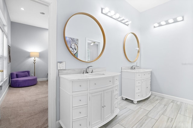 bathroom featuring a healthy amount of sunlight, two vanities, a sink, and baseboards