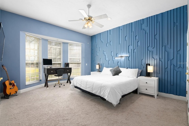 bedroom featuring a ceiling fan, carpet, an accent wall, and baseboards