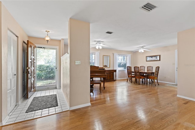 foyer entrance with light wood finished floors, baseboards, visible vents, and ceiling fan