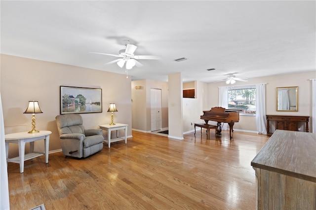 living area with light wood finished floors, baseboards, visible vents, and ceiling fan