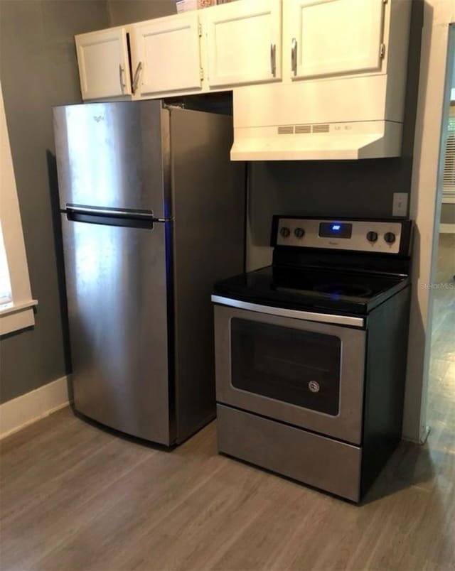 kitchen with appliances with stainless steel finishes, light wood-style floors, white cabinets, and under cabinet range hood