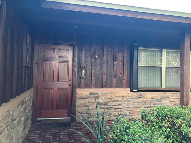 doorway to property featuring stone siding and board and batten siding