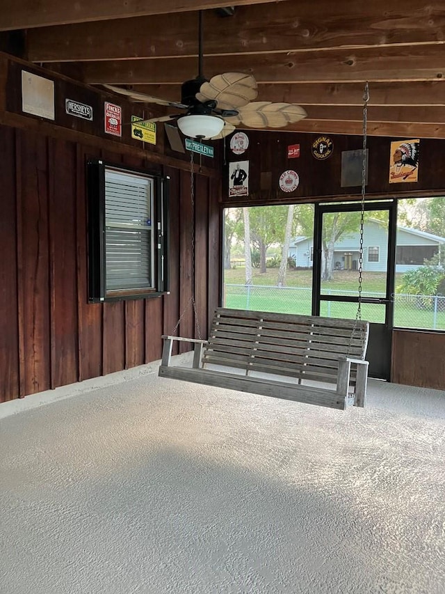 exterior space featuring wooden walls, a ceiling fan, and carpet flooring