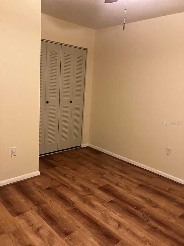 unfurnished bedroom featuring a closet, baseboards, and wood finished floors