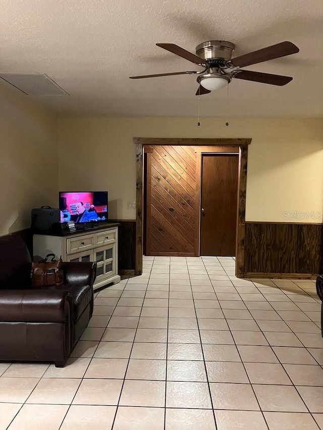 living room with light tile patterned floors, a ceiling fan, and a textured ceiling