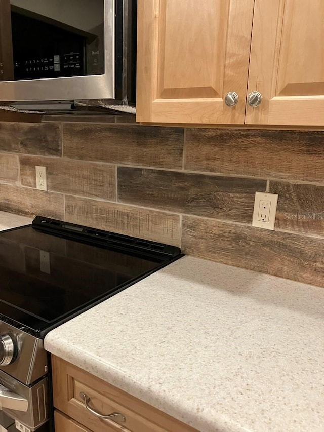 details with stainless steel appliances, light brown cabinetry, light countertops, and tasteful backsplash