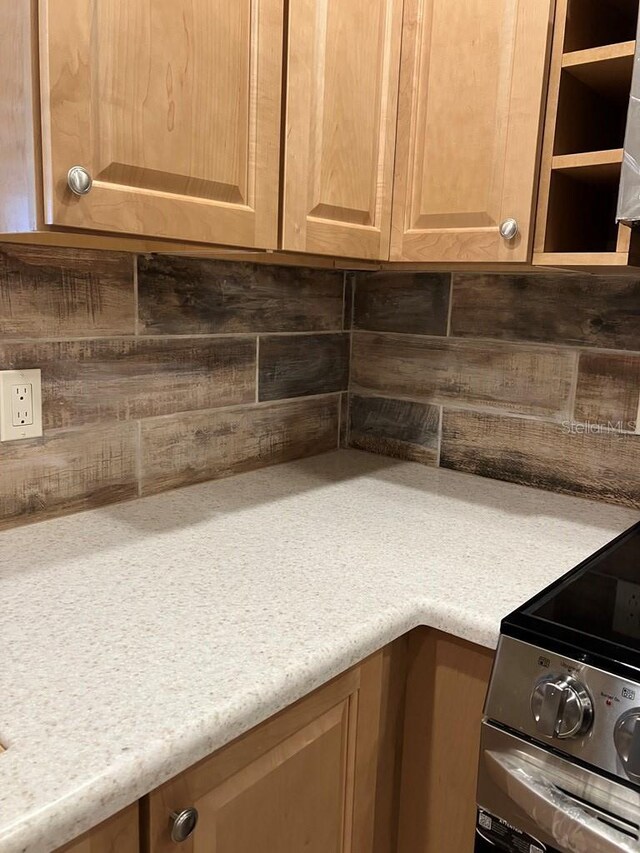 room details featuring light brown cabinets, light countertops, stainless steel electric range oven, and decorative backsplash