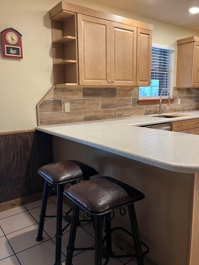 kitchen featuring wainscoting, a kitchen breakfast bar, light countertops, and light brown cabinetry