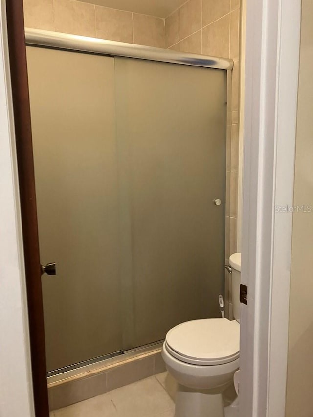 full bath featuring tile patterned flooring, a shower stall, and toilet