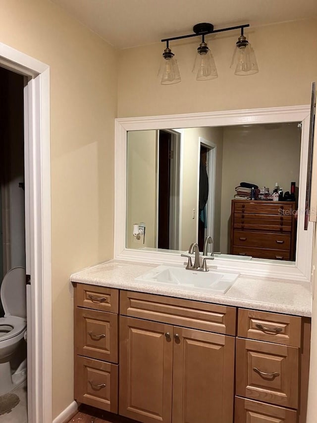 bathroom featuring baseboards, vanity, and toilet