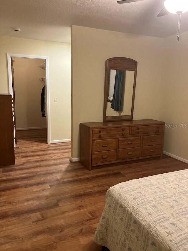 bedroom featuring a ceiling fan, baseboards, dark wood finished floors, and a textured ceiling