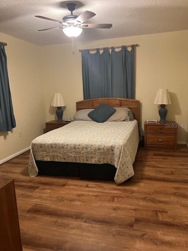 bedroom with a textured ceiling, ceiling fan, wood finished floors, and baseboards