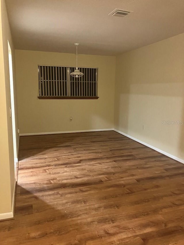 empty room featuring visible vents, baseboards, and wood finished floors