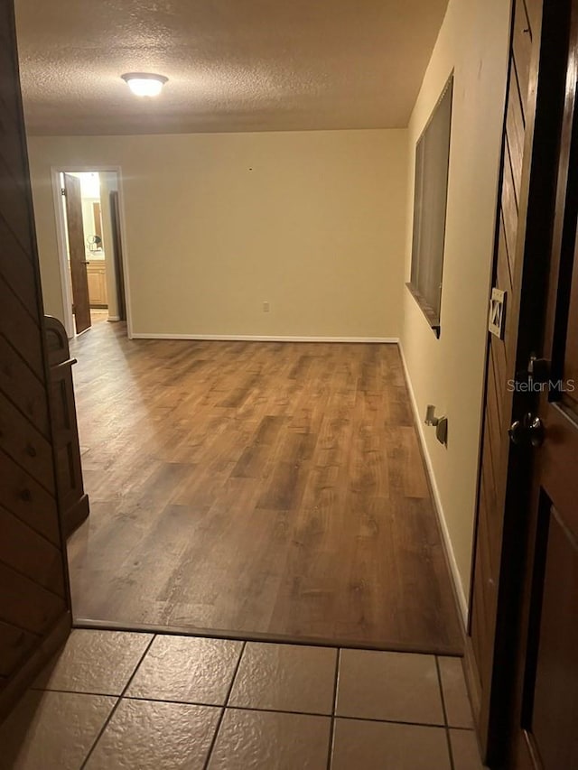 hallway featuring a textured ceiling, baseboards, and wood finished floors