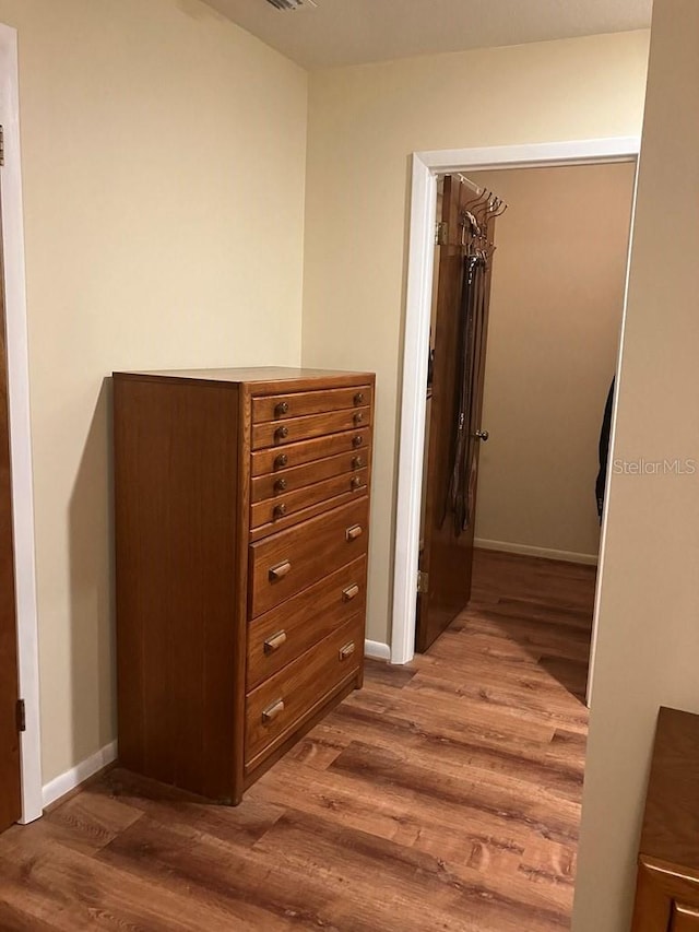 hallway with visible vents, baseboards, and wood finished floors