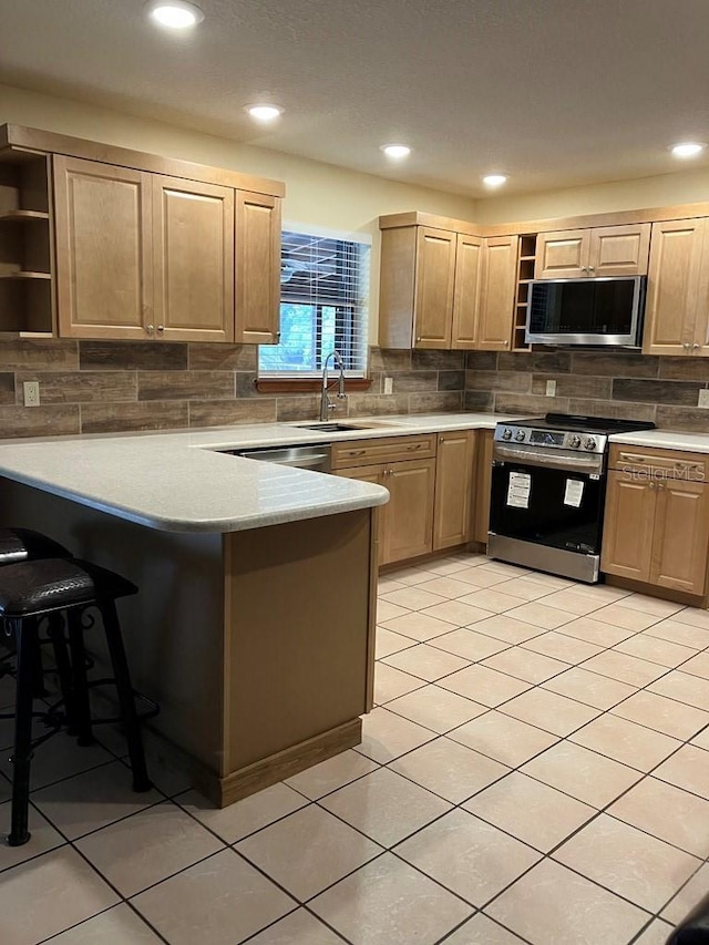 kitchen featuring appliances with stainless steel finishes, a peninsula, light brown cabinets, open shelves, and a sink