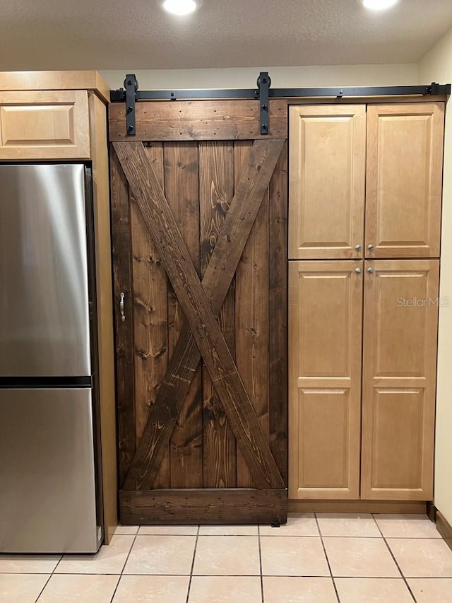 details with a barn door, a textured ceiling, and freestanding refrigerator