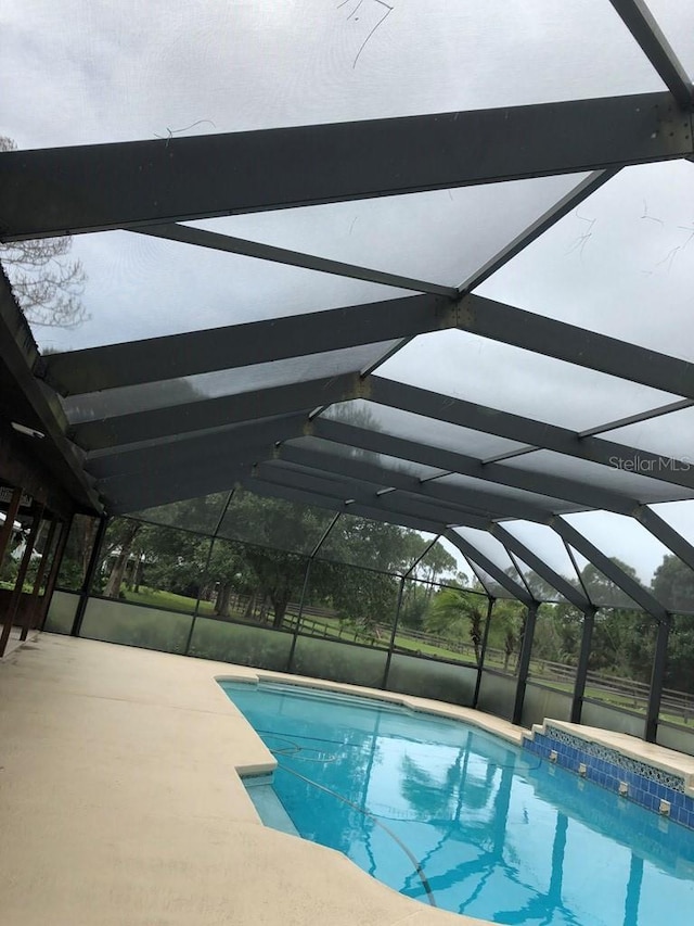 pool featuring glass enclosure and a patio area