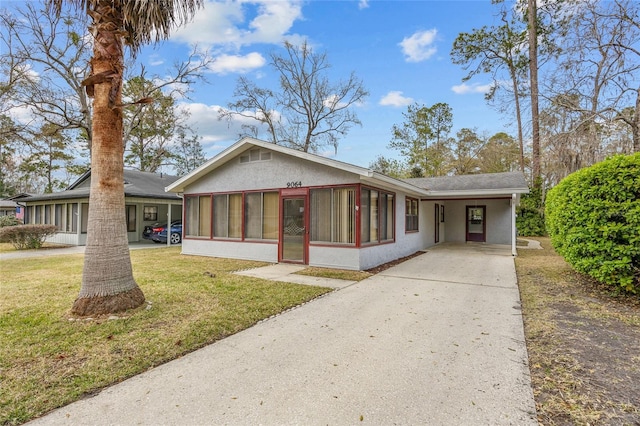 view of front of property with a carport, a sunroom, driveway, and a front lawn