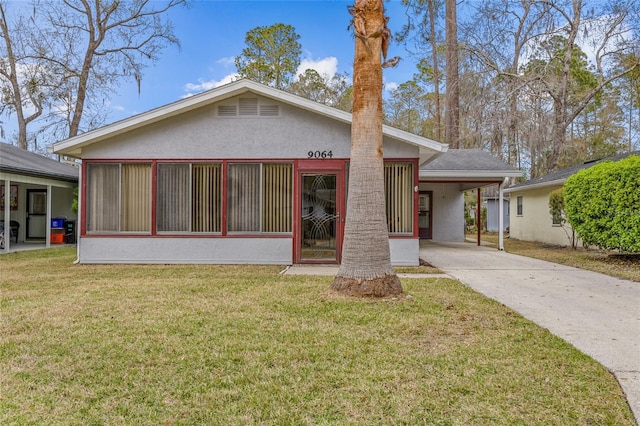 back of property featuring concrete driveway, a lawn, a carport, and stucco siding