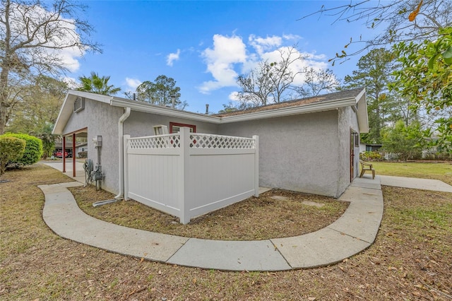 view of home's exterior with fence and stucco siding