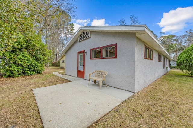 rear view of property with a yard, a patio, and stucco siding